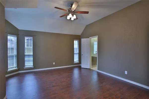 a view of an empty room with window chandelier fan and wooden floor