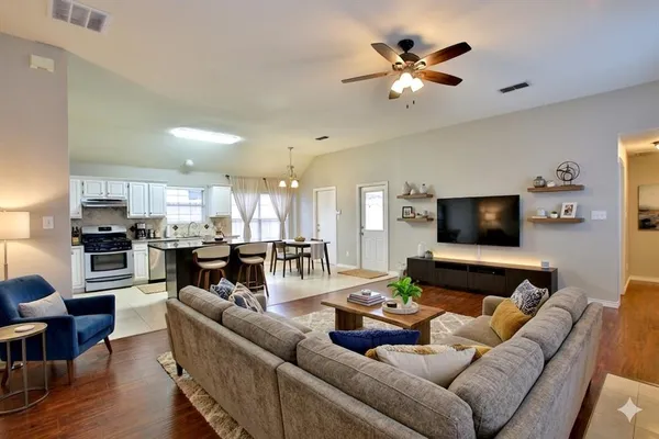 a living room with furniture kitchen view and a flat screen tv