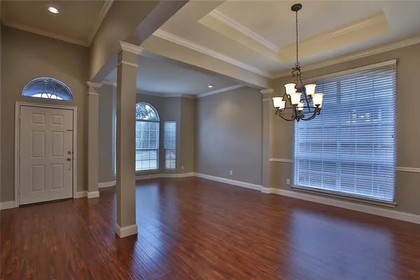 a view of an empty room with wooden floor chandelier and entryway