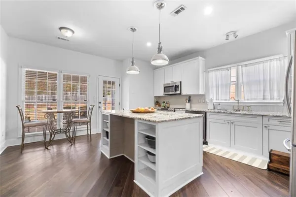 a kitchen with a stove a window and chairs