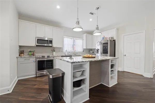 a kitchen with kitchen island granite countertop a sink a counter top space stainless steel appliances and cabinets