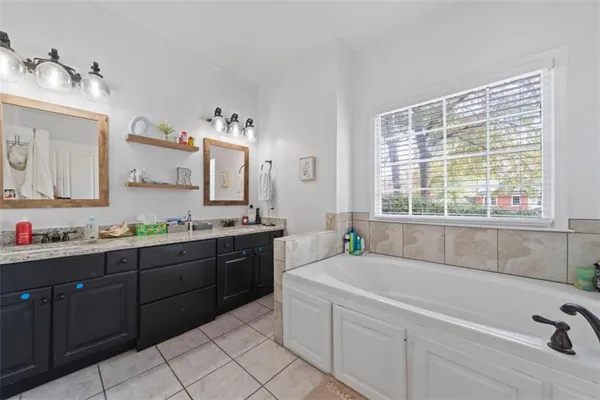 a spacious bathroom with a granite countertop sink mirror and a bathtub