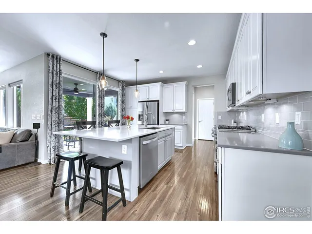 a kitchen with stainless steel appliances kitchen island a table chairs and a refrigerator