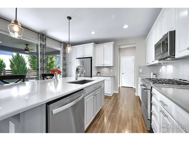 a kitchen with stainless steel appliances kitchen island granite countertop a table chairs sink and cabinets