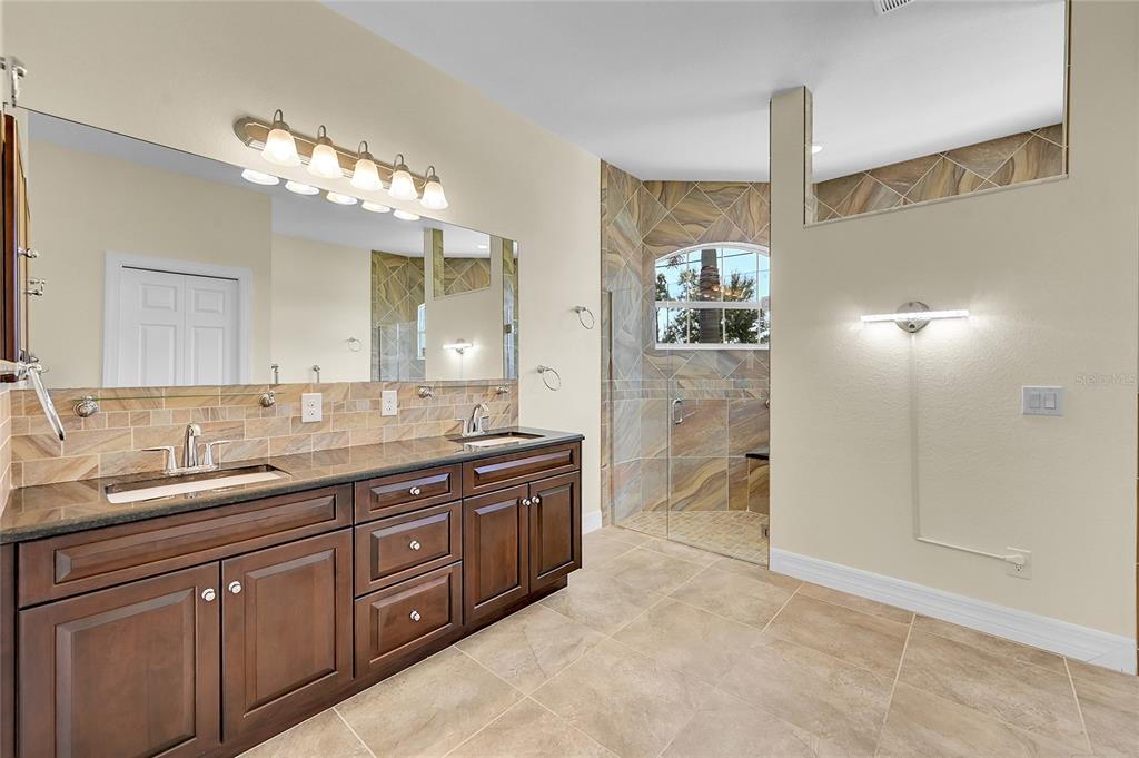 233 Fairway Road Rotonda West, FL 33947 - Photo 32 of 63 a spacious bathroom with a granite countertop sink a mirror and a shower