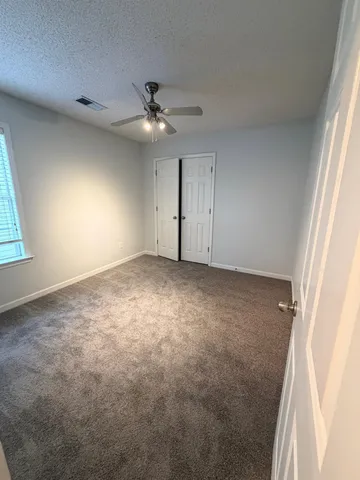 an empty room with windows and fan