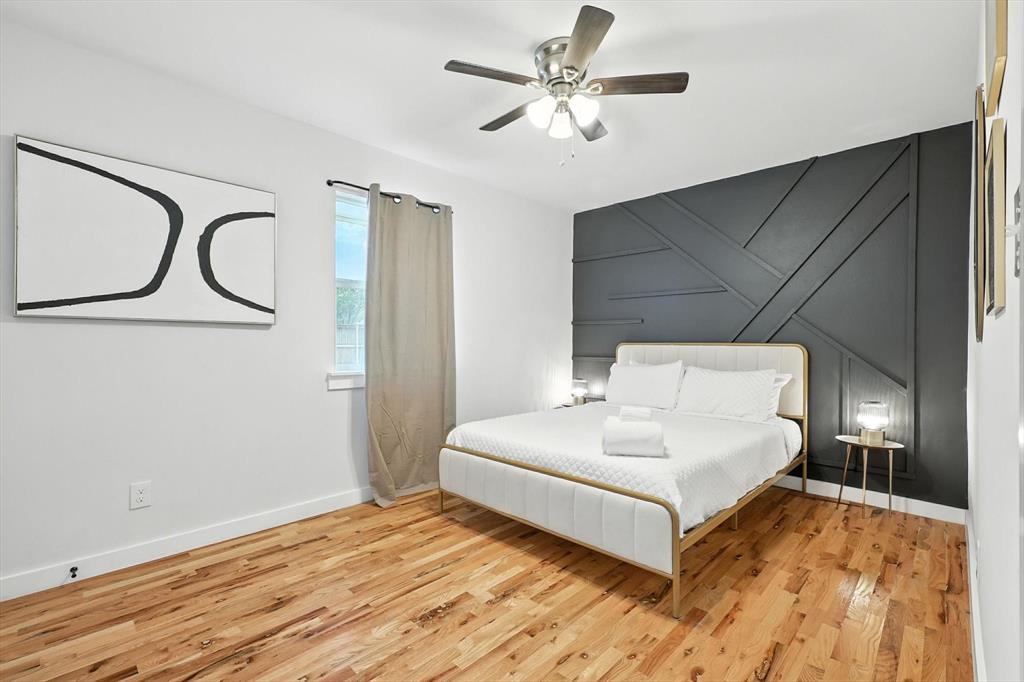 1009 Walnut Street Irving, TX 75060 - Photo 22 of 39 Bedroom with an accent wall, a decorative wall, wood finished floors, and a ceiling fan