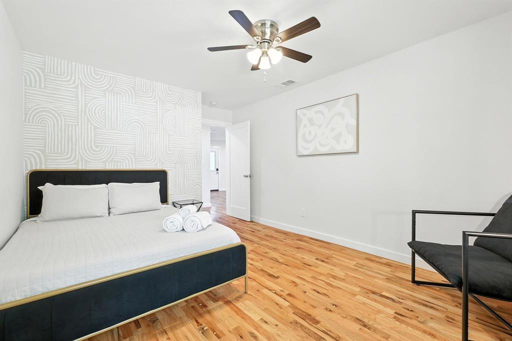 1009 Walnut Street Irving, TX 75060 - Photo 26 of 39 Bedroom with light wood-type flooring, wallpapered walls, a ceiling fan, and an accent wall