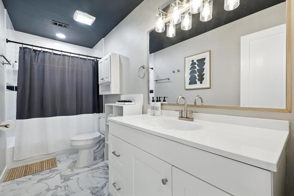 1009 Walnut Street Irving, TX 75060 - Photo 27 of 39 Bathroom featuring vanity, shower / tub combo with curtain, and light marble finish flooring