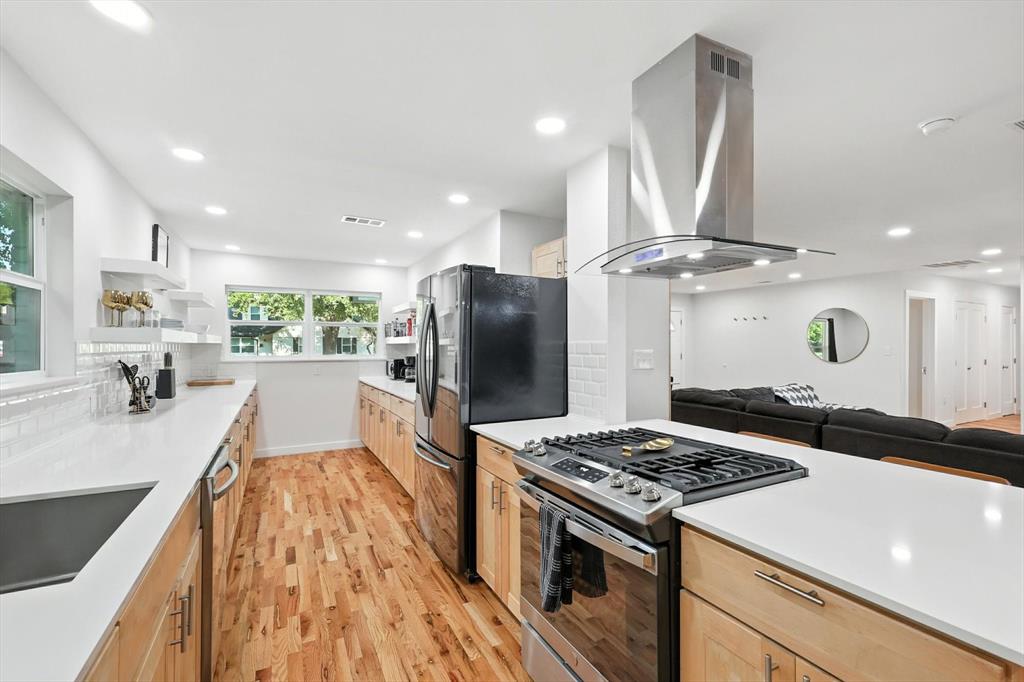 1009 Walnut Street Irving, TX 75060 - Photo 39 of 39 Kitchen with light brown cabinets, appliances with stainless steel finishes, open floor plan, open shelves, and island range hood