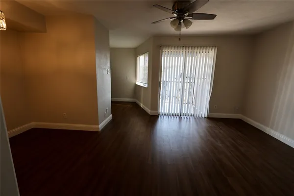 an empty room with wooden floor chandelier fan and windows