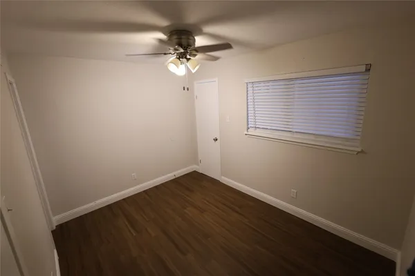 en empty room with wooden floor and fan