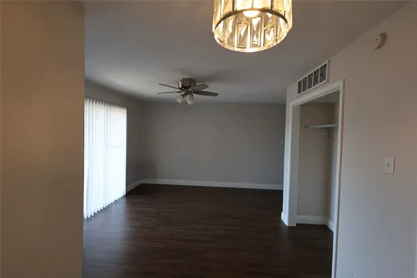 an empty room with wooden floor windows and closet