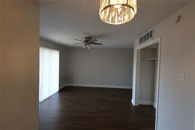 an empty room with wooden floor windows and closet