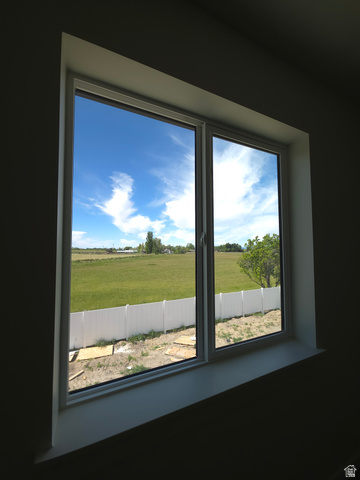 1267 West 2350 South Perry, UT 84302 - Photo 7 of 20 Double-paned window with a white frame, offering expansive views of open fields and a distant tree line