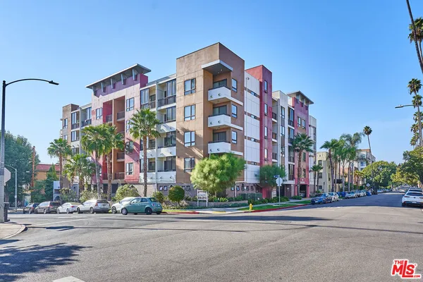 a front view of multi story residential apartment building with yard and traffic signal
