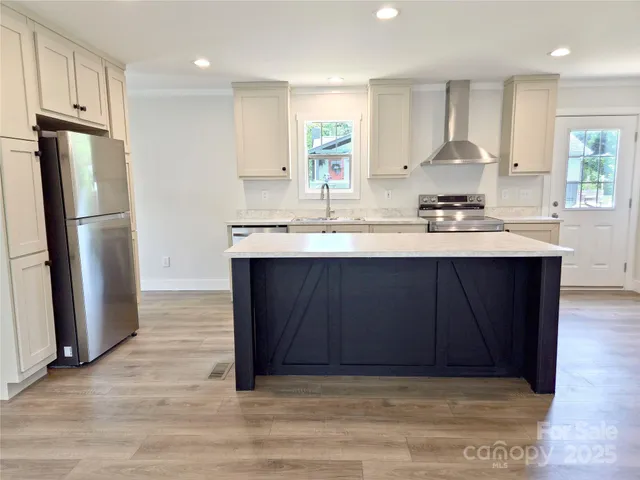 a kitchen with stainless steel appliances granite countertop a stove a sink dishwasher and a refrigerator with wooden floor