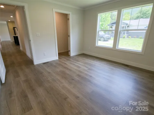 a view of an empty room with wooden floor and closet