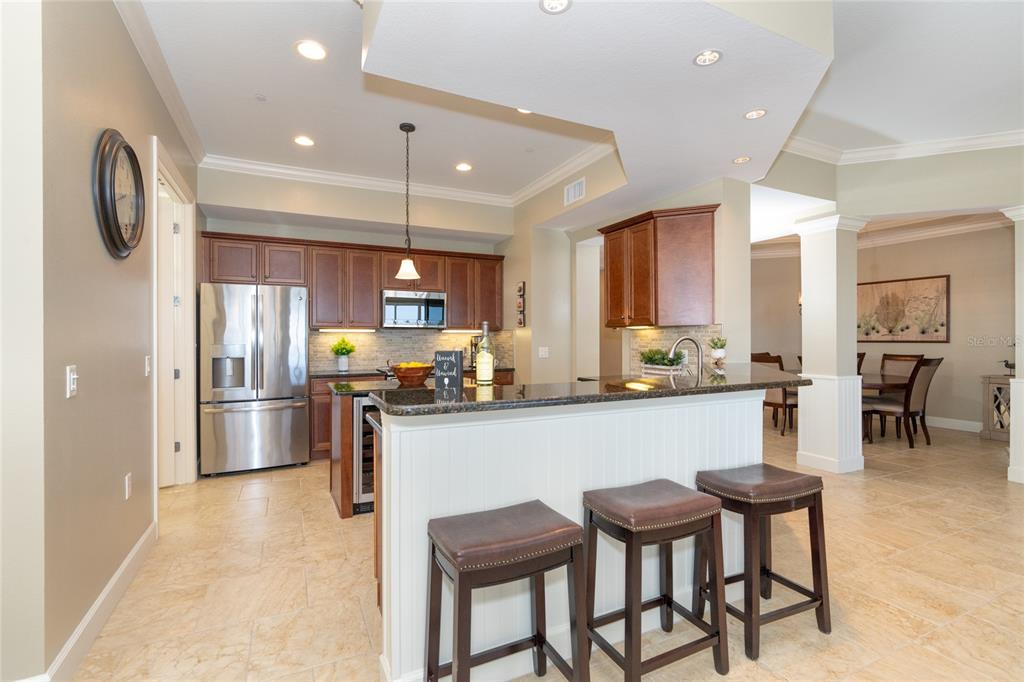 10501 Amberjack Way, Unit 402 Englewood, FL 34224 - Photo 10 of 45 a kitchen with stainless steel appliances granite countertop a refrigerator a stove top oven a sink a dining table and chairs with wooden floor