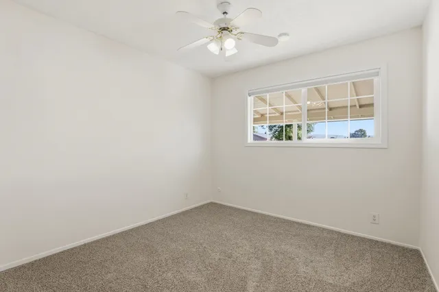 an empty room with a window and a fan