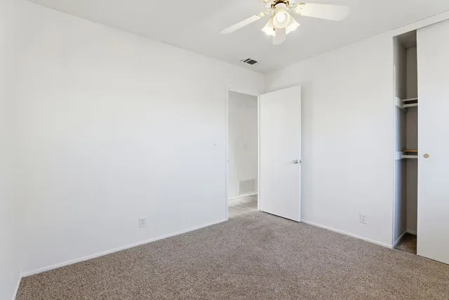 an empty room with a chandelier fan and windows