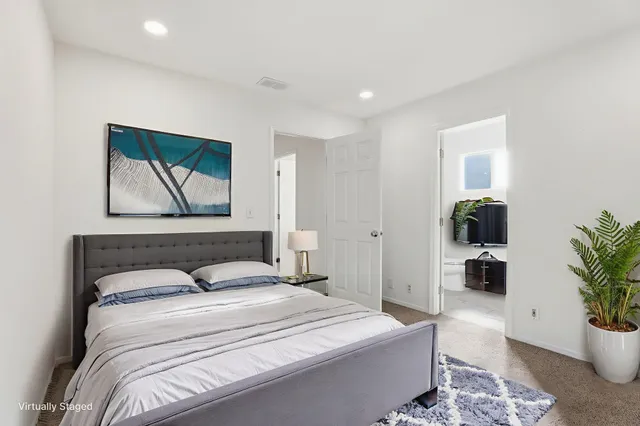 a bedroom with a large bed and a potted plant