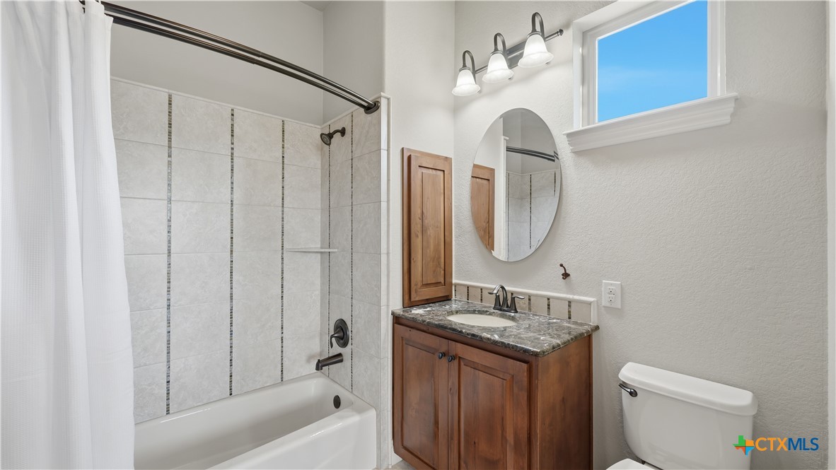 1035 Thunderbolt Rd Canyon Lake Canyon Lake, TX 78133 - Photo 33 of 48 a bathroom with a granite countertop sink a toilet and a mirror