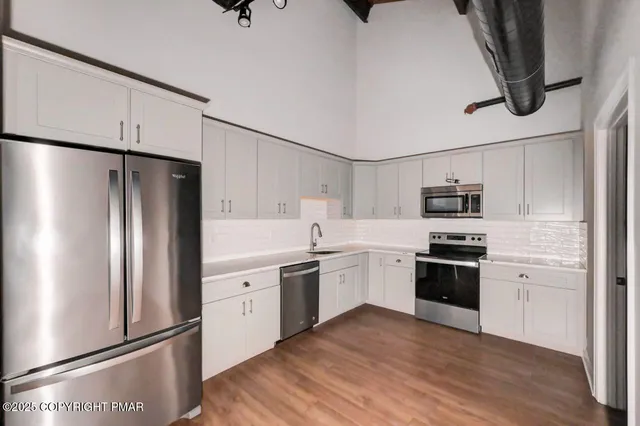 a kitchen with cabinets stainless steel appliances a sink and wooden floor