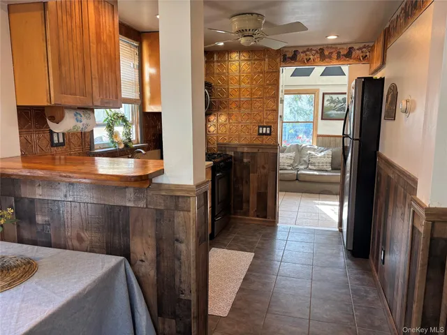 a kitchen with kitchen island a counter top space wooden floor and a refrigerator