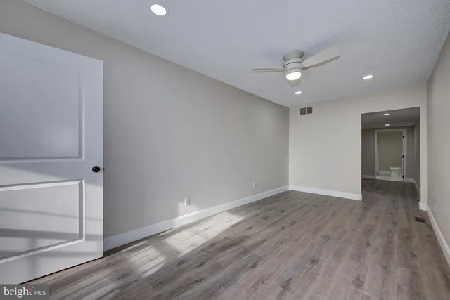 an empty room with wooden floor closet and windows