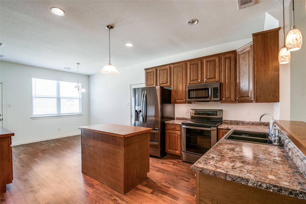 2412 Colquitt Road Terrell, TX 75160 - Photo 4 of 24 a kitchen with stainless steel appliances granite countertop a stove top oven a sink dishwasher a refrigerator and a microwave