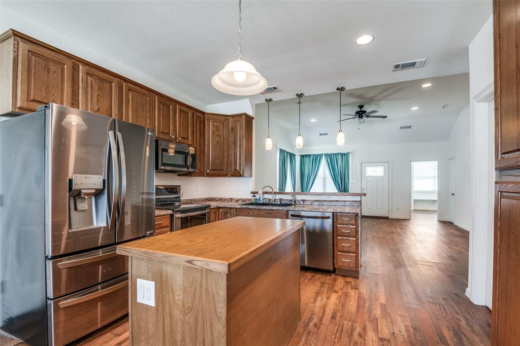 2412 Colquitt Road Terrell, TX 75160 - Photo 8 of 24 a kitchen with stainless steel appliances granite countertop a refrigerator a sink dishwasher a stove and white countertops with wooden floor