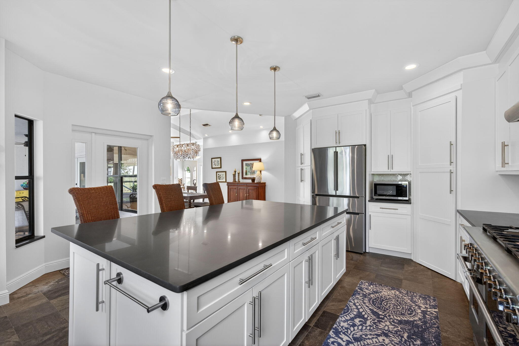 1488 Southeast Colony Way Jupiter, FL 33478 - Photo 18 of 51 a large kitchen with stainless steel appliances granite countertop a kitchen island a stove a refrigerator a dining table and chairs