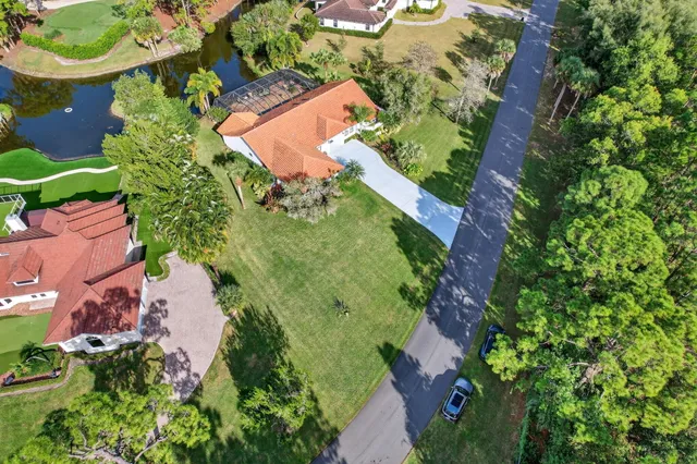 an aerial view of a residential houses with outdoor space and trees all around