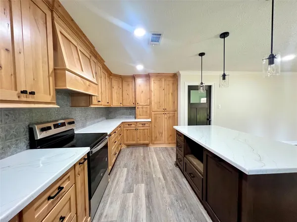 a kitchen with stainless steel appliances a stove a sink a refrigerator a center island and wooden floor