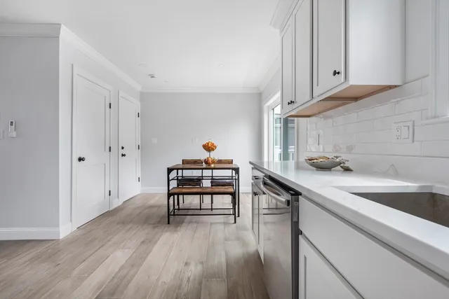 a kitchen with stainless steel appliances white cabinets and wooden floor
