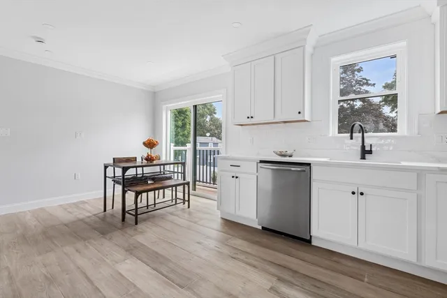 a kitchen with stainless steel appliances white cabinets and wooden floor