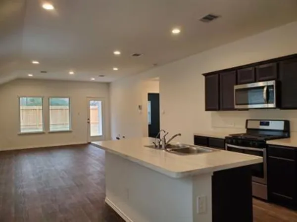 a kitchen with granite countertop a sink and a stove top oven with wooden floor