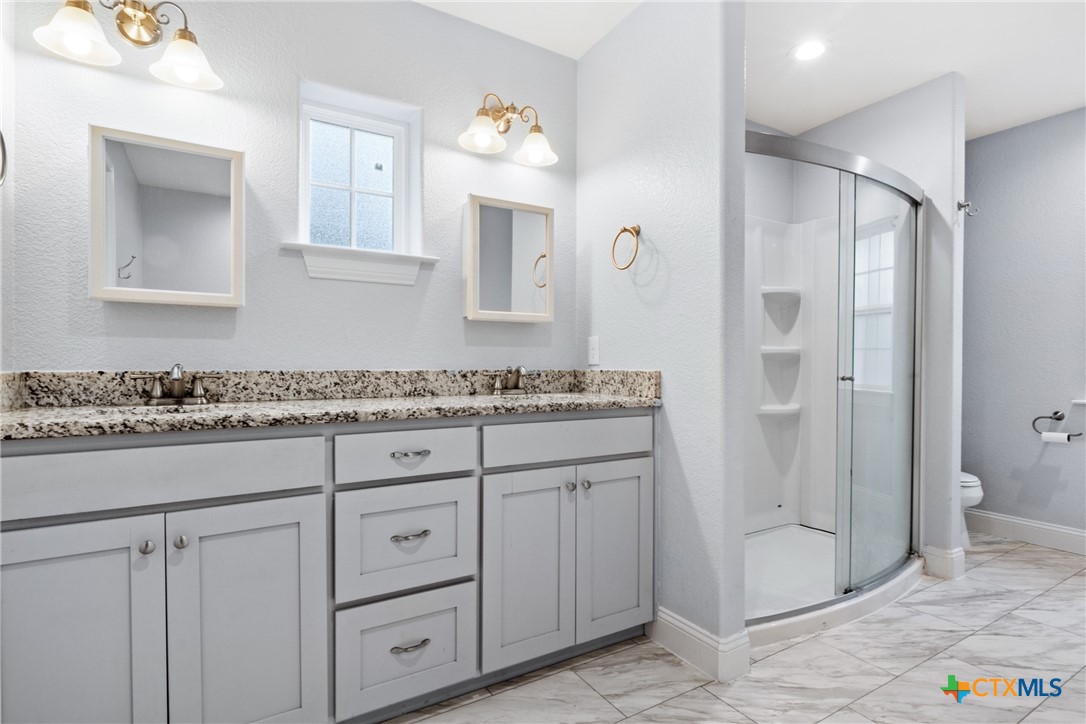 275 Woodruff Road Waco, TX 76705 - Photo 5 of 45 a bathroom with a granite countertop sink a mirror and a shower
