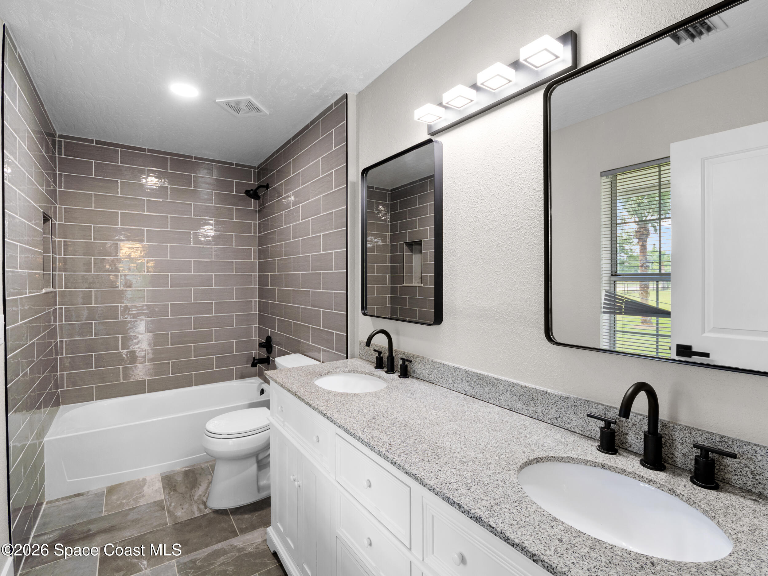 3480 Weber Road Malabar, FL 32950 - Photo 16 of 45 a bathroom with a granite countertop sink a toilet a mirror a bathtub and shower