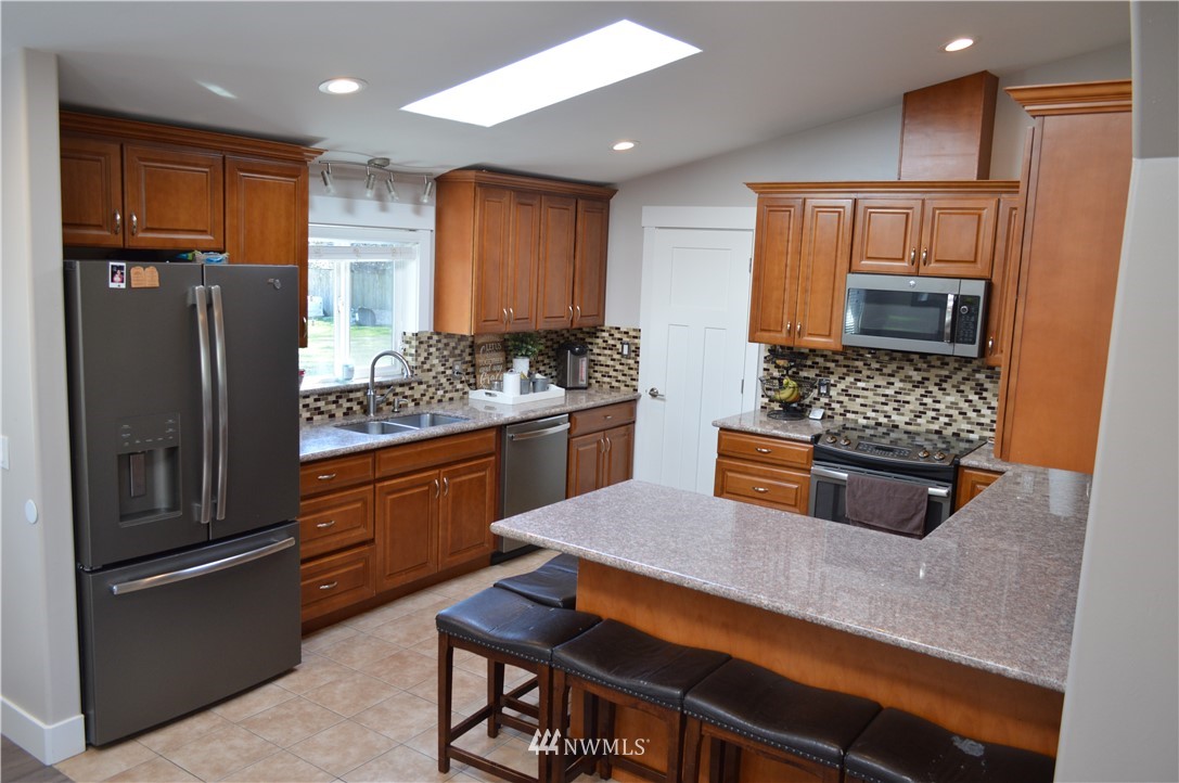 6760 Old Guide Road Lynden, WA 98264 - Photo 14 of 37 a kitchen with stainless steel appliances kitchen island granite countertop a refrigerator and a stove top oven
