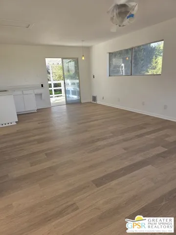 a view of an empty room with wooden floor and a window