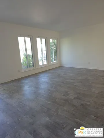 a view of a big room with wooden floor and windows