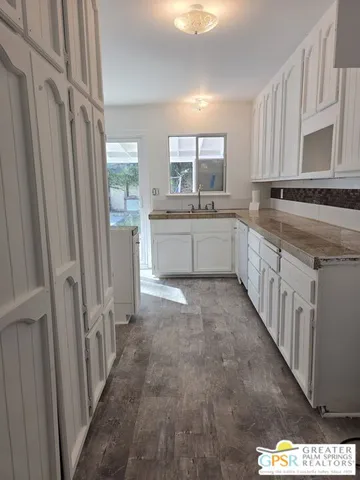 a large white kitchen with a sink a window and stainless steel appliances