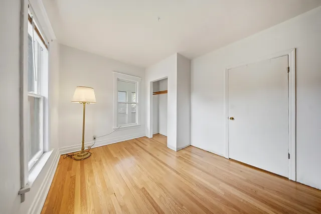 a view of a bedroom with wooden floor and a window