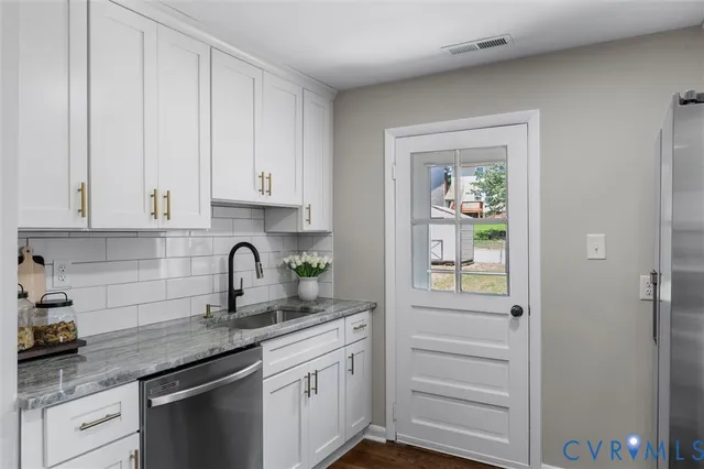 a kitchen with granite countertop stainless steel appliances white cabinets and a sink