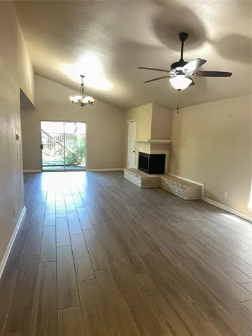 a view of a livingroom with wooden floor a ceiling fan and windows
