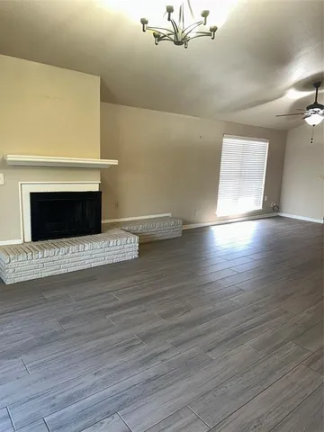 a view of an empty room with wooden floor and a fireplace