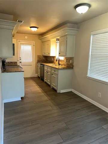 a kitchen with granite countertop a sink cabinets and wooden floor