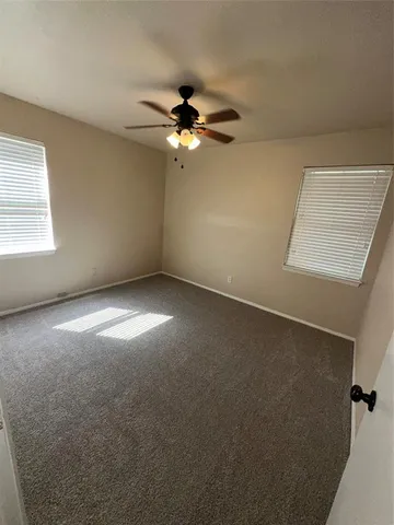 an empty room with windows and fan